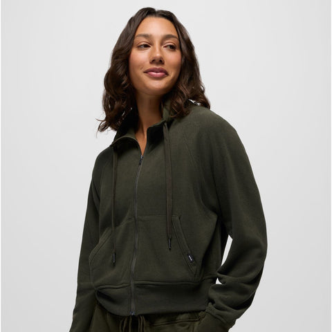 Woman wearing a green zip-up hoodie and pants on a light gray background