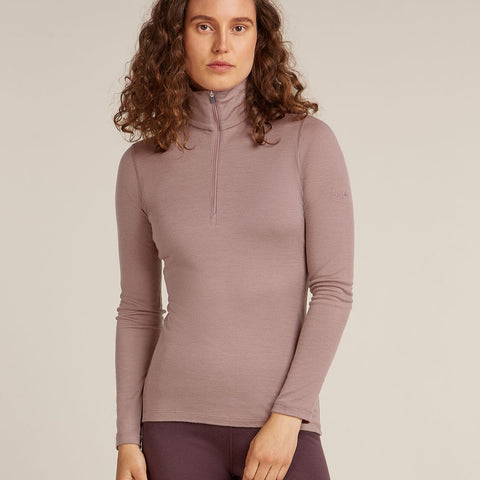 Woman wearing a mauve long-sleeve top with a quarter zip on a beige background