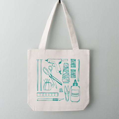 Turquoise crafting tools including hot glue gun, scissors, pin cushion, glue, knitting and crochet needles screen printed on a tote