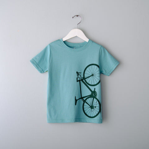 Teal t-shirt with a bicycle design on a white hanger against a gray background
